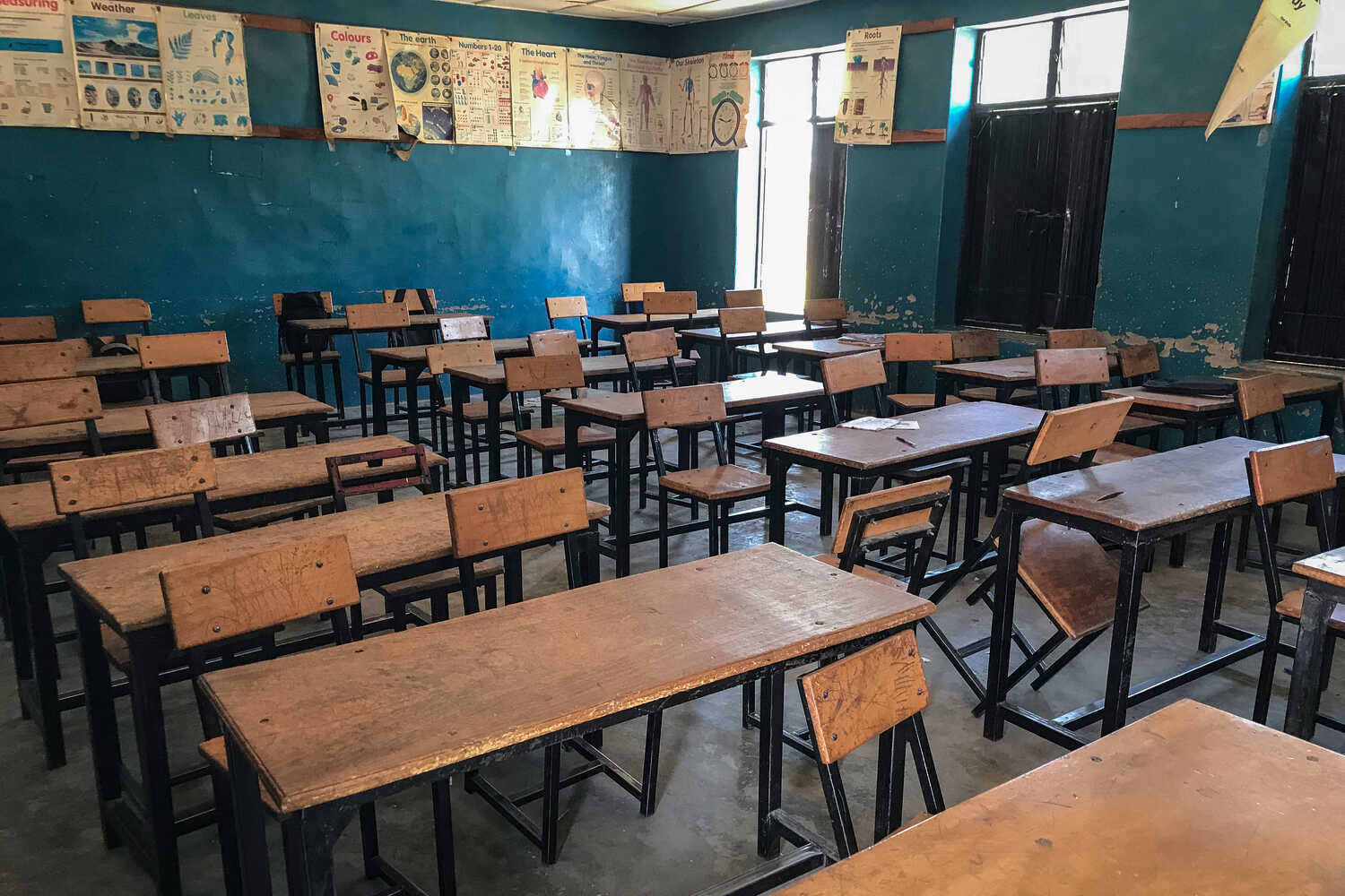 An empty classroom with desks and chairs arranged in rows.