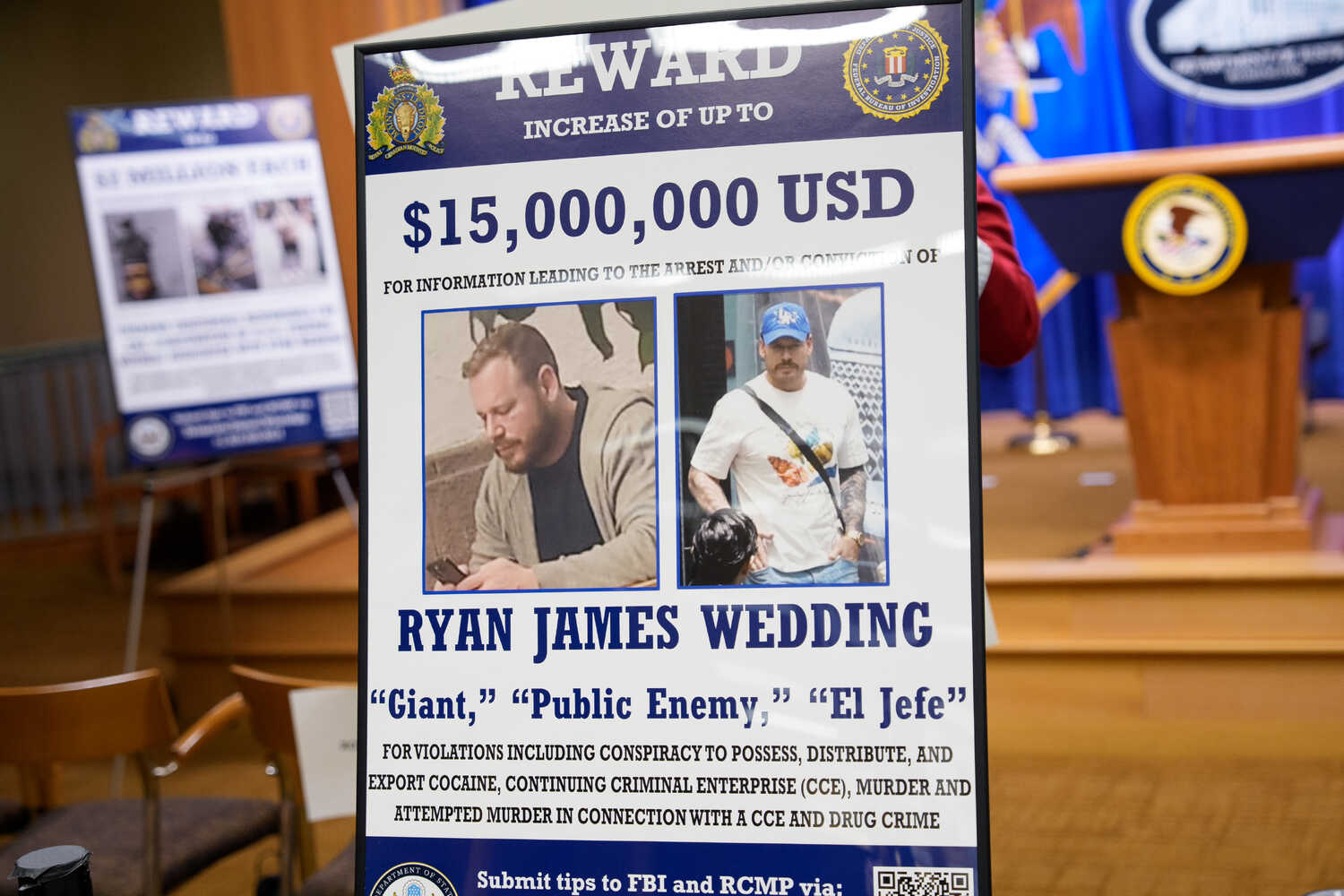A poster with two photos of a person wanted by the F.B.I. is shown near a lectern.