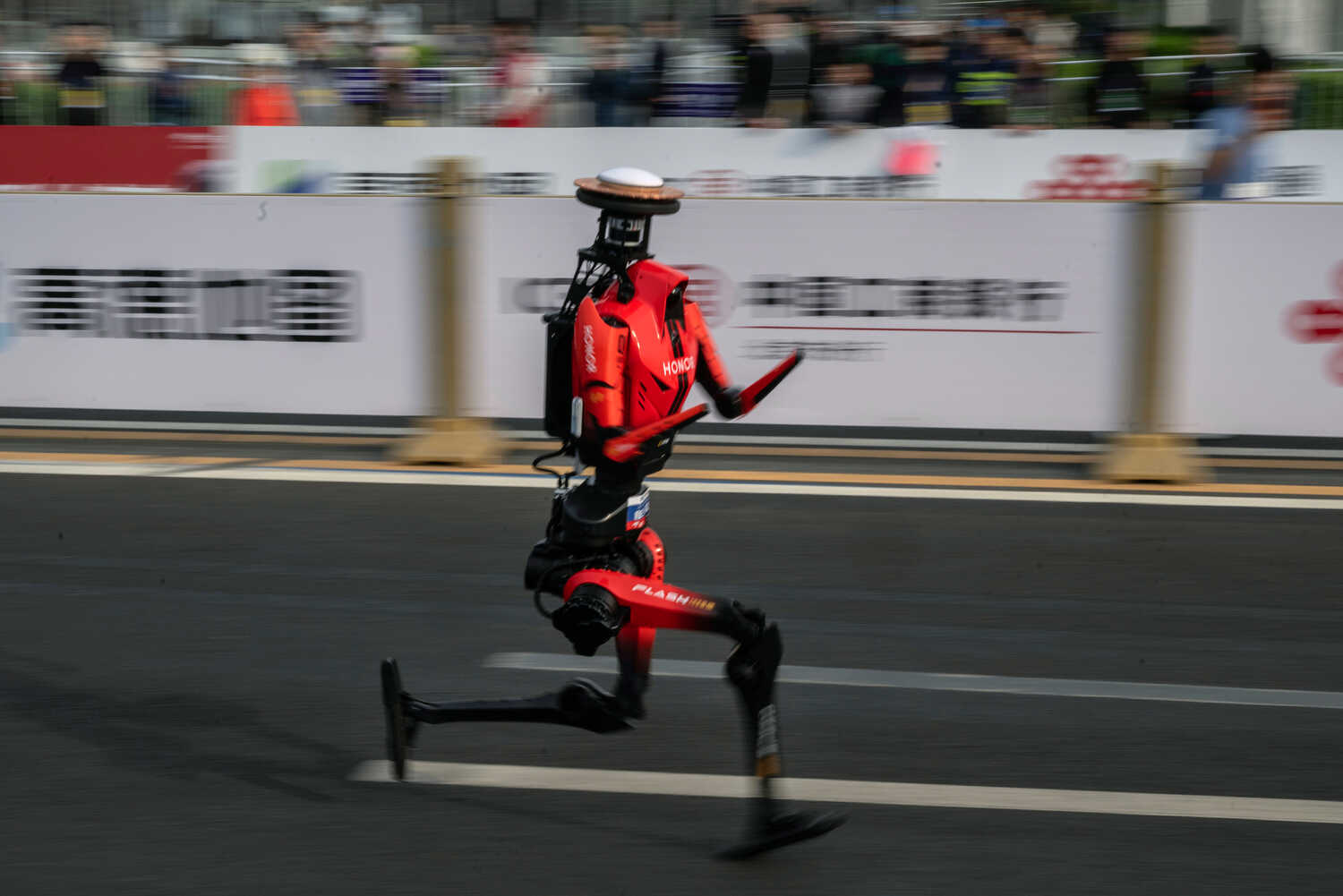 A bright-red 5-foot-5 humanoid robot strides on a road in Beijing.