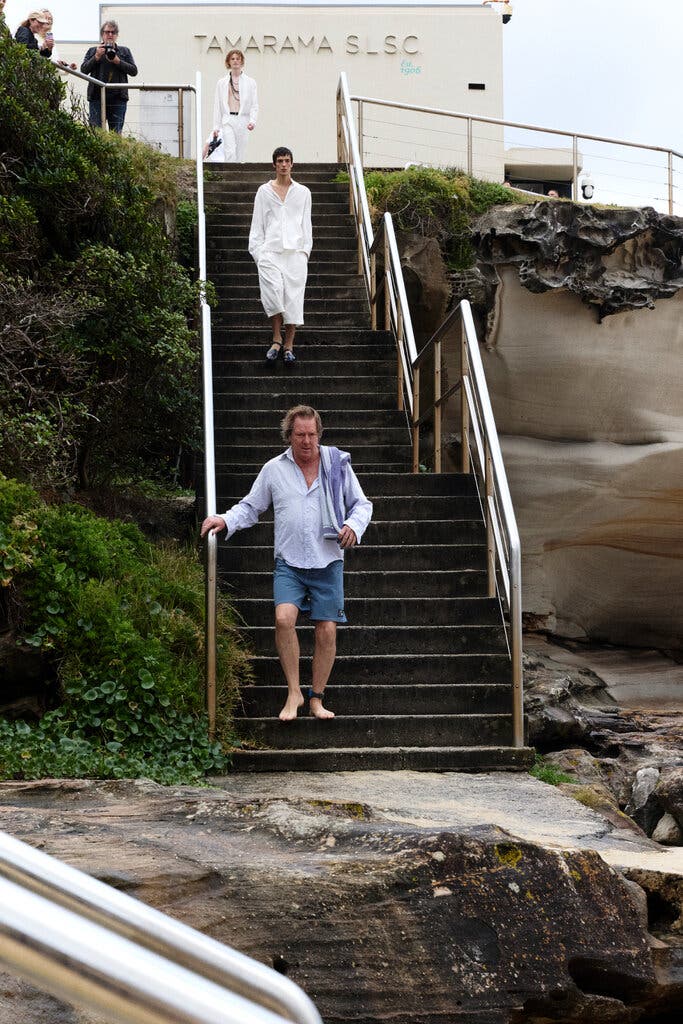Men walking down steps toward a beach.