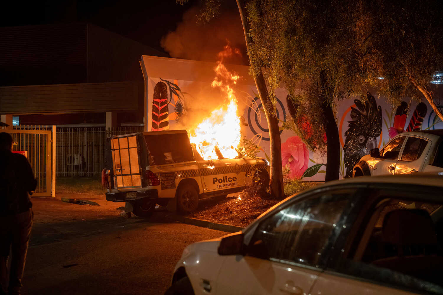 A police car rests on the roadside with flames coming out of the cabin